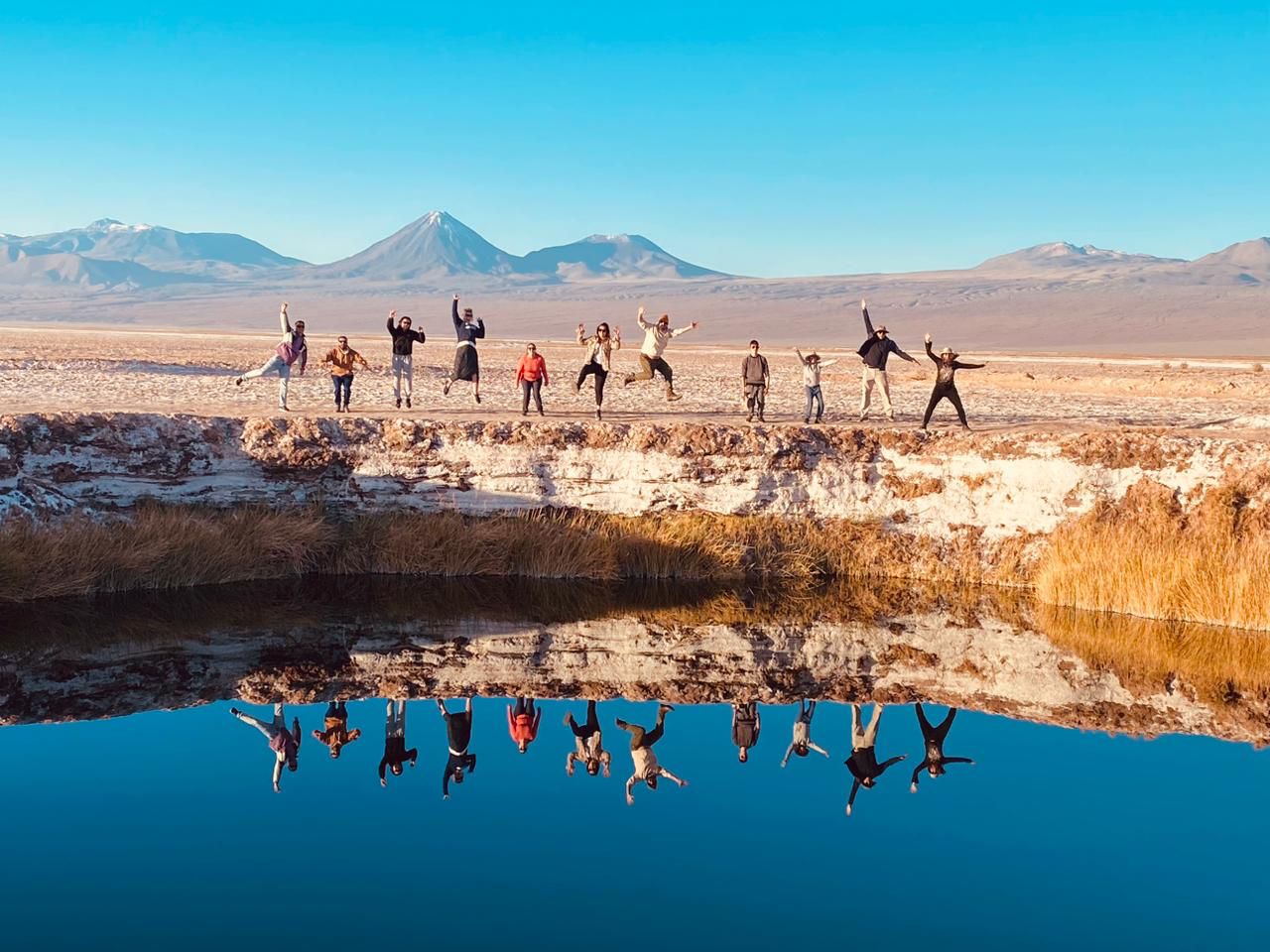 Grupo de turistas saltando em paisagem de Laguna Cejar, próximo a San Pedro de Atacama.